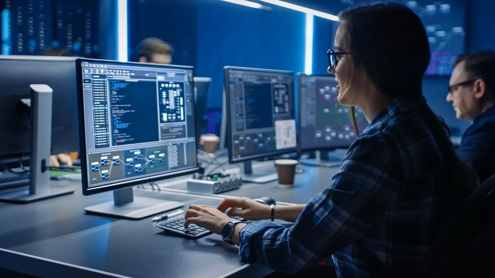 Smart Female IT Programer Working on Desktop Computer in Data Center System Control Room. Team of Young Professionals Doing Code Programming