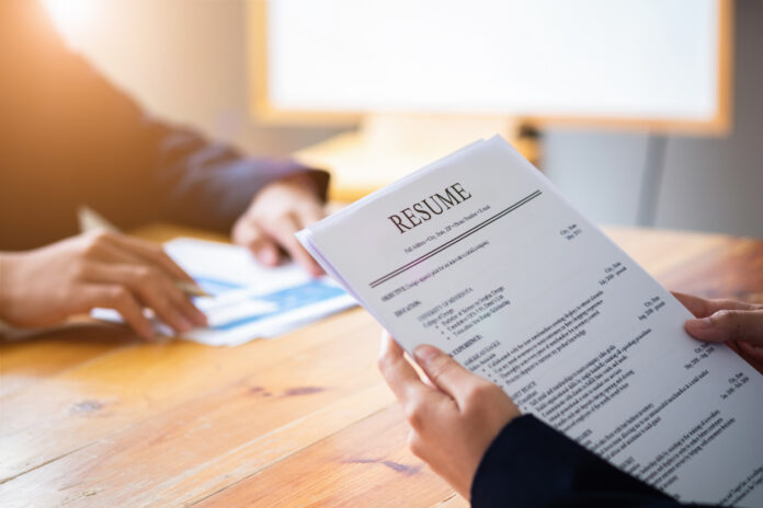 Interviewer reading a resume, Person submits job application, Person describe yourself to interviewer, Close up view of job interview in office, focus on resume, recruiter considering application, hr manager making hiring decision